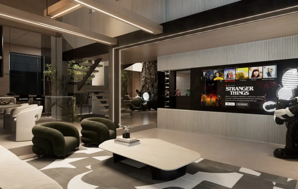 A contemporary open-concept living room featuring a recessed media wall with a large television, olive green velvet swivel chairs, and a sculptural coffee table, accented by large designer art figures and a floating staircase.